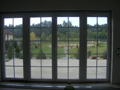 okno w salonie z widokiem na ogród i las