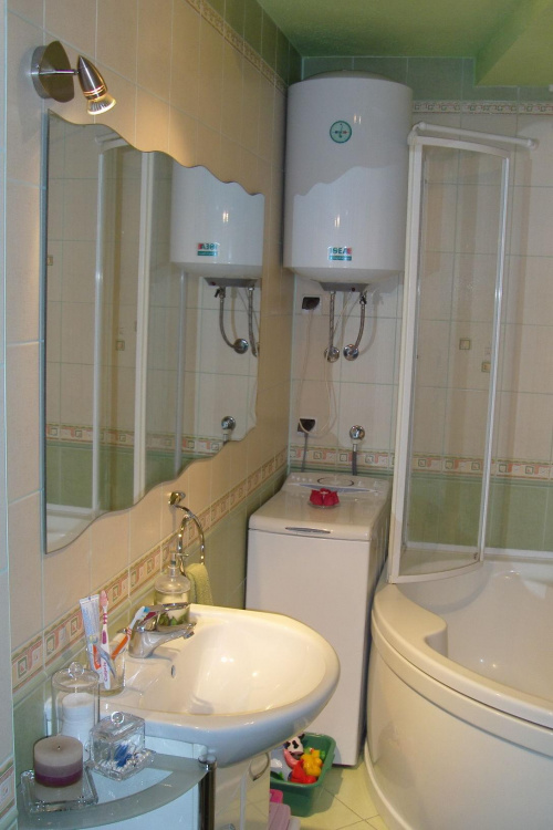 łazienka - umywalka Koło; szklany, półkolisty parawan wanny częściowo otwarty